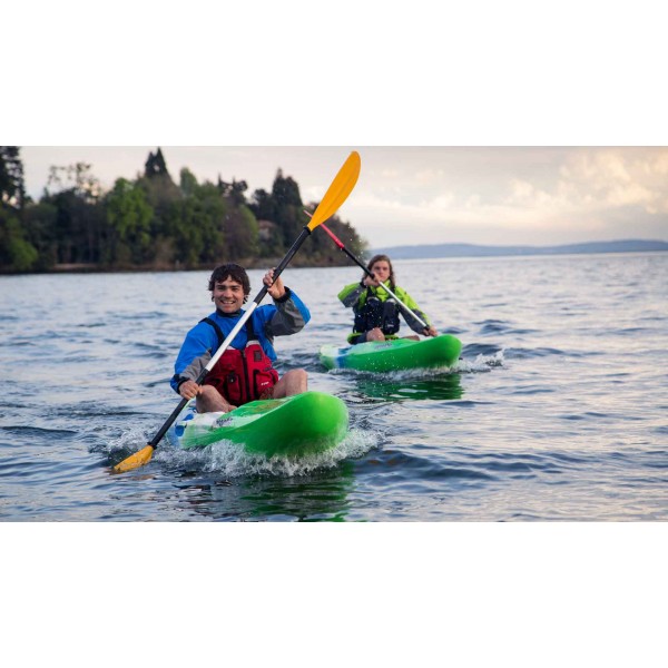Two kayakers paddle together on the lake with touring kayaks and paddles.
